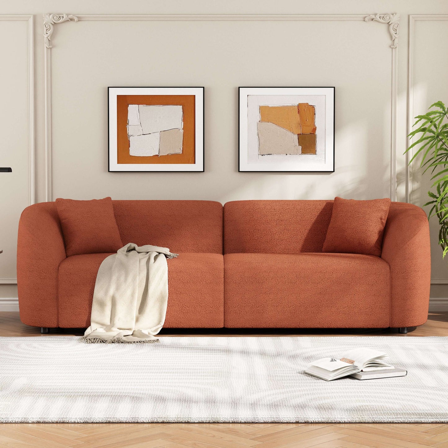 Contemporary sloped arm boucle upholstered sofa in terracotta with artwork and plants in a modern living room.