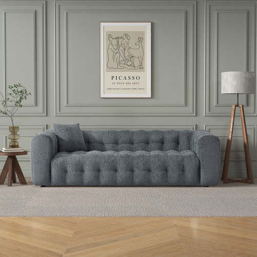 A modern living room with the Ashcroft Furniture Eden Modern Boucle Bubble Sofa 90, premium boucle upholstery, a side table with a plant, a floor lamp, and a framed Picasso print on the gray paneled wall above the sofa.