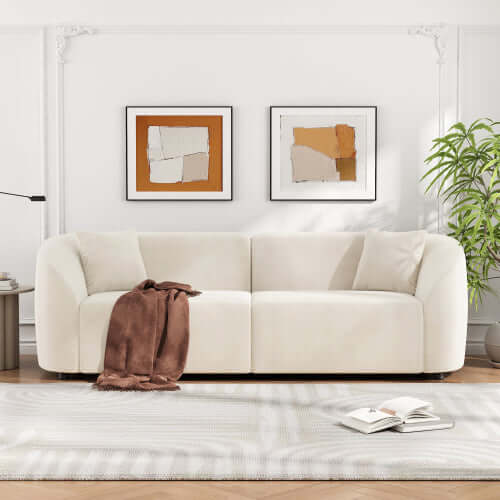 Contemporary sloped arm boucle upholstered sofa in cream with brown throw, stylish living room decor.