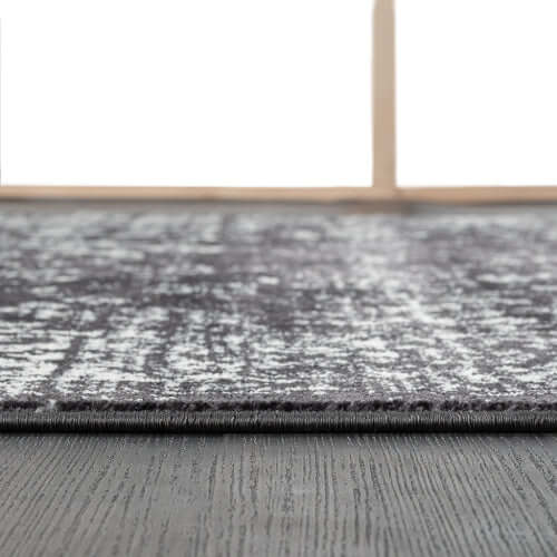 Distressed vintage Persian styled woven area rug on dark wood floor, showcasing classic patterns and modern durability.