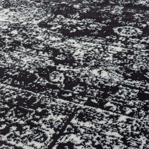 Distressed vintage Persian styled woven area rug featuring intricate patterns in black and white.