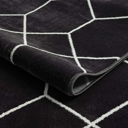 Close-up of Trellis black and white geometric woven area rug, showcasing bold pattern and soft texture.
