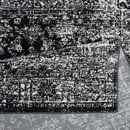 Distressed vintage Persian styled woven area rug close-up showcasing intricate patterns and textures in black and white.