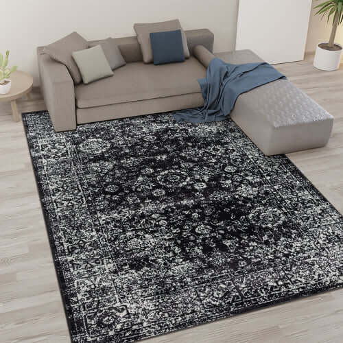 Distressed vintage Persian styled woven area rug 8x10ft on light hardwood floor in a modern living room design.