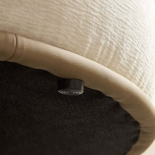 Close-up of the underside of a chaise sofa, showcasing the soft cream fabric and protective base.