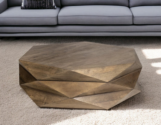 The Home Roots Hexagonal Solid Wood Coffee Table With Storage 48 adds geometric elegance to any space, its faceted design casting striking shadows on a light carpet in front of a gray sofa.