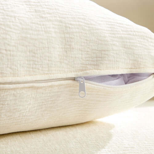 Cream decorative pillow close-up showing zipper detail on plush fabric.