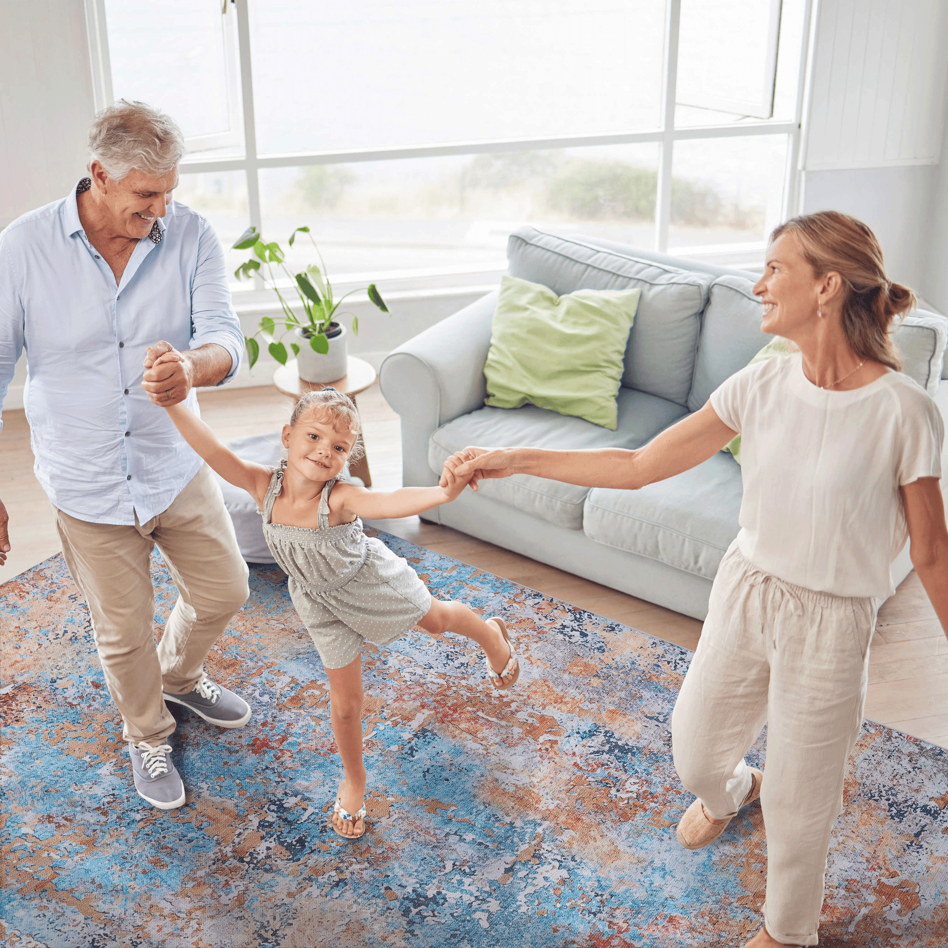 Family dancing together on a vibrant multi-colored abstract area rug in a cozy living room.