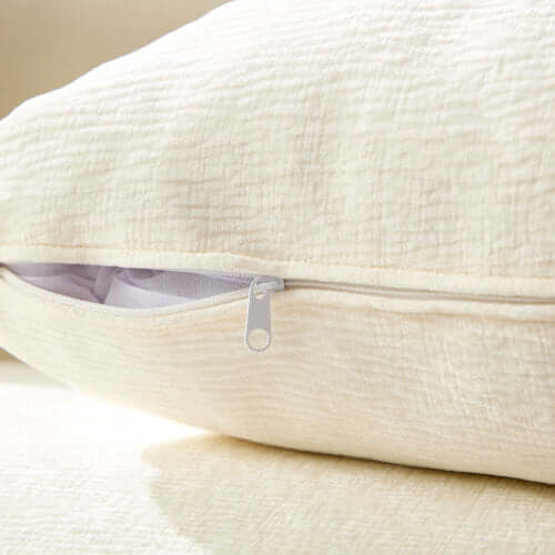 Close-up of soft cream pillow with zipper detail, showcasing its plush texture and quality design.