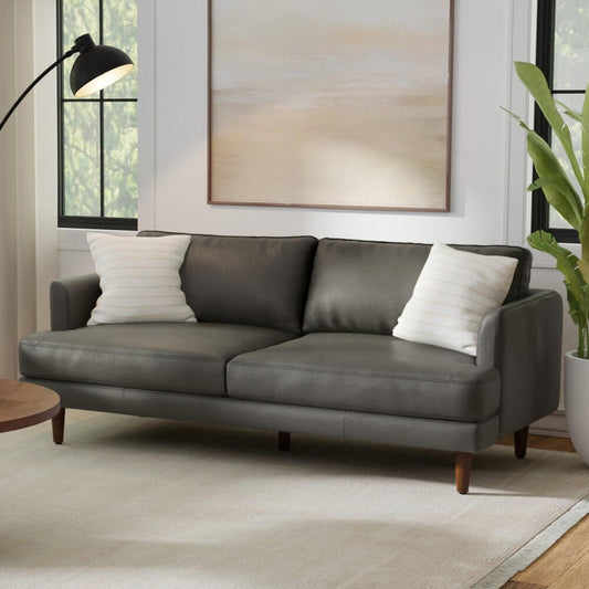 76" Black Leather Sofa With Brown Legs in a cozy living room setting with modern decor