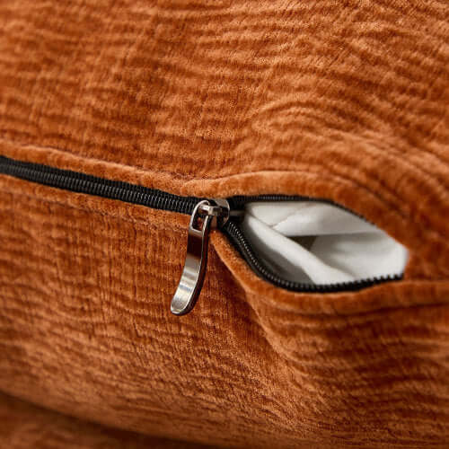 Close-up of the zipper detail on an orange plush sofa cushion, highlighting quality craftsmanship and texture.