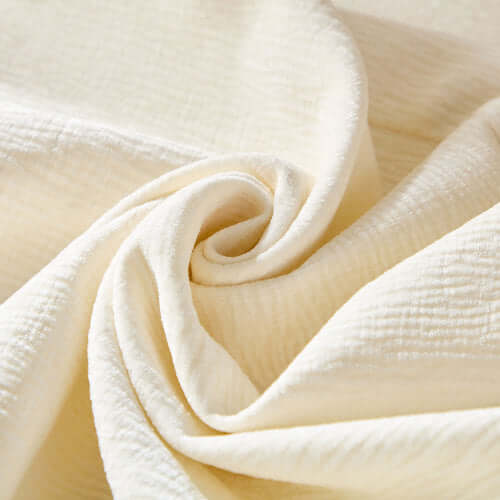 Close-up of soft, textured cream fabric, perfect for upholstery in a cozy sectional sofa.