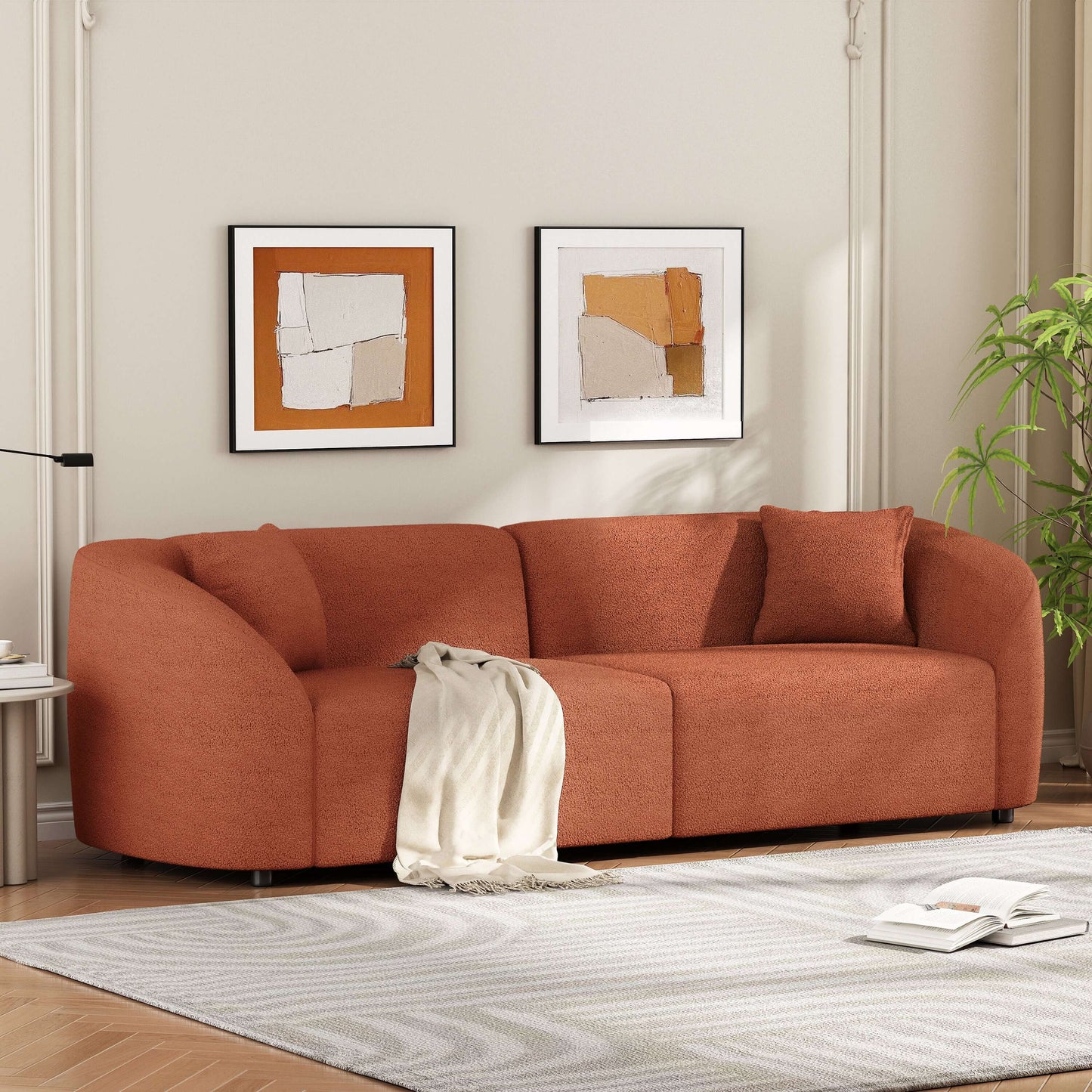 Contemporary sloped arm boucle upholstered sofa in rust color, featuring curved design and cozy throw blanket in a modern living room.