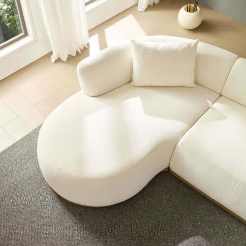 Rounded L-shaped chaise sofa sectional in cream color with plush cushion, enhancing modern living room decor.