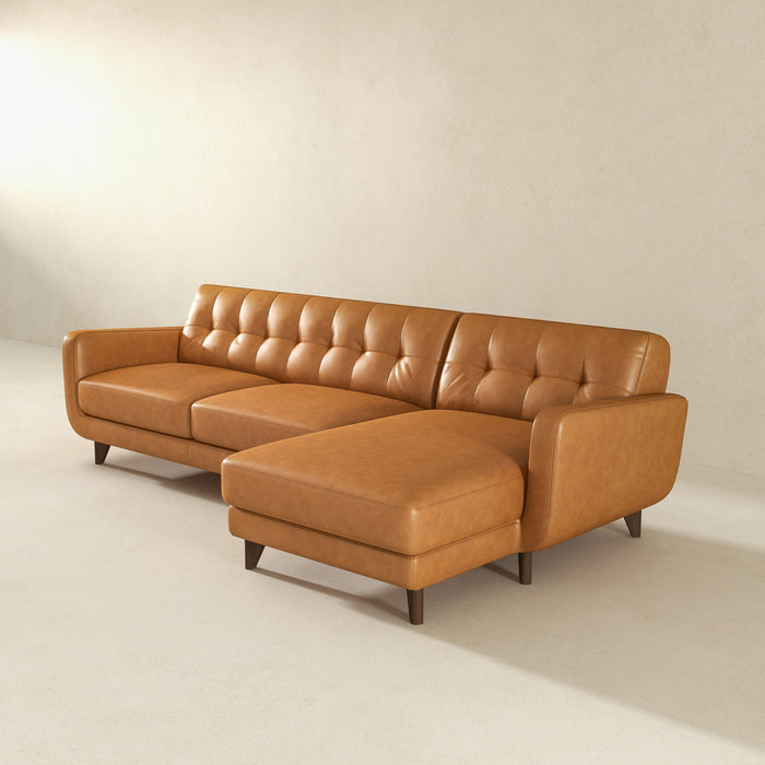 The Ashcroft Furniture Allison MCM Leather Chaise Sofa Sectional 113 in tan genuine leather features a tufted backrest, right-side chaise lounge, and wooden legs, beautifully set in a minimalist room with light walls and floors.