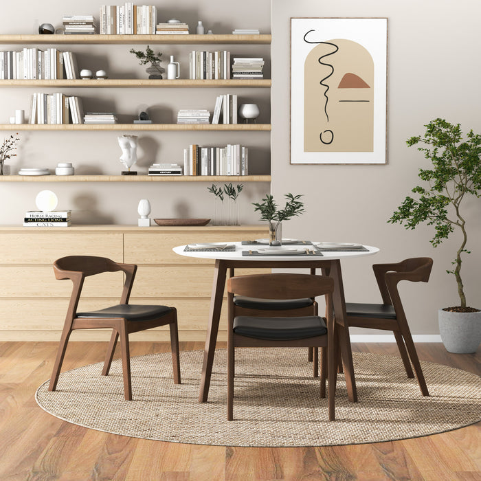 A modern dining room with the Alina MCM Round Walnut Wood Dining Table 43 by Ashcroft Furniture, four wooden chairs, a circular rug, bookshelves, sideboard, abstract wall art, and a potted plant on wood flooring; customizable finishes available.