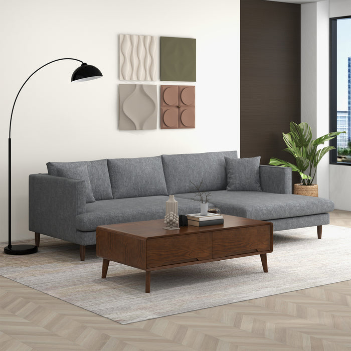 A modern living room featuring the Ashcroft Furniture Blake Velvet Upholstered L-Shape Chaise Sofa Sectional 107, paired with a wooden coffee table, black arc floor lamp, wall panels, potted plant, large window, light rug, and wood flooring.