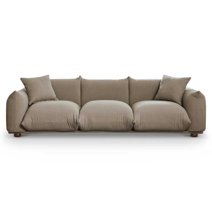The Ashcroft Furniture Kely Boho Chic Fabric Sofa 100” in taupe features plush boucle upholstery, three large seat cushions, two matching throw pillows, and rounded armrests, shown against a plain white background.