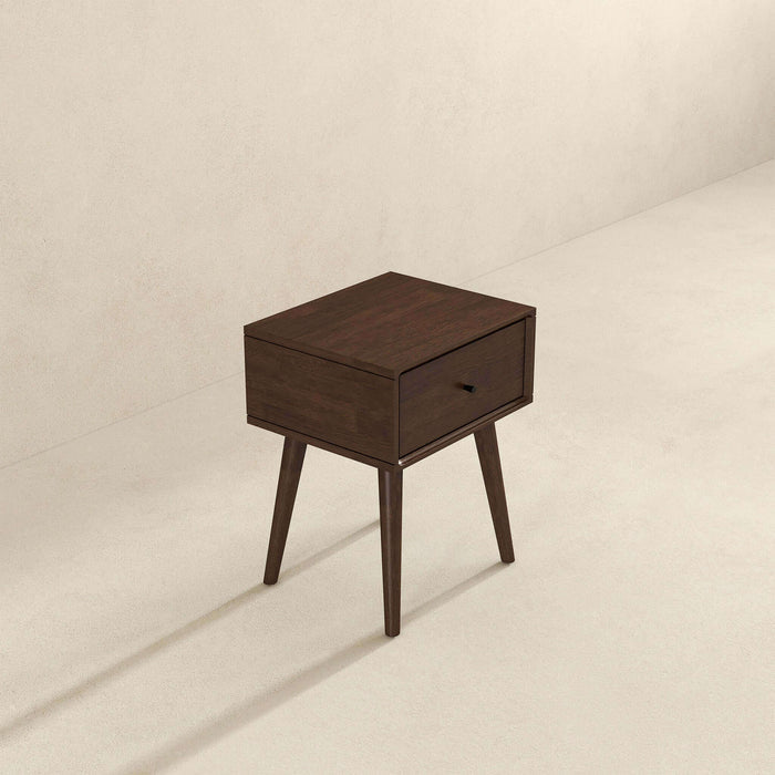 The Avery Solid Wood Nightstand with Drawer by Ashcroft Furniture Co. features a modern walnut finish, single drawer, and four angled legs, shown on a light floor against a beige wall.
