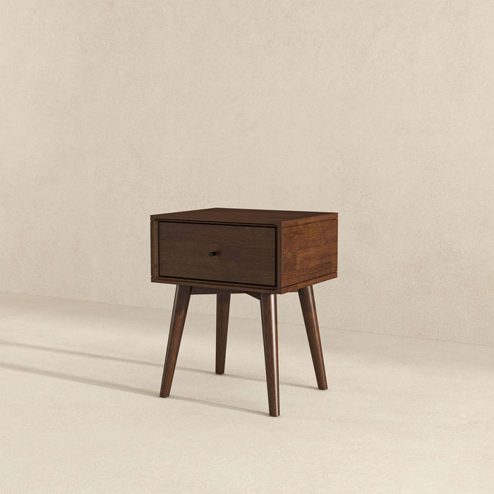 The Avery Solid Wood Nightstand with Drawer by Ashcroft Furniture Co. showcases a mid-century modern design, walnut finish, single drawer, and four angled legs, styled against a plain beige background.