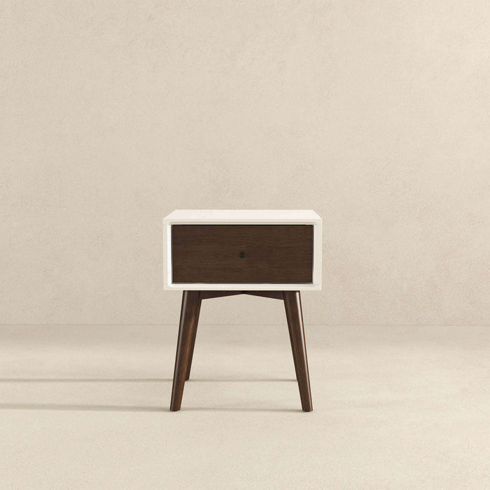 The Avery Solid Wood Nightstand with Drawer by Ashcroft Furniture Co. features a walnut-finished drawer, white frame, and angled wooden legs, displayed against a plain beige background.