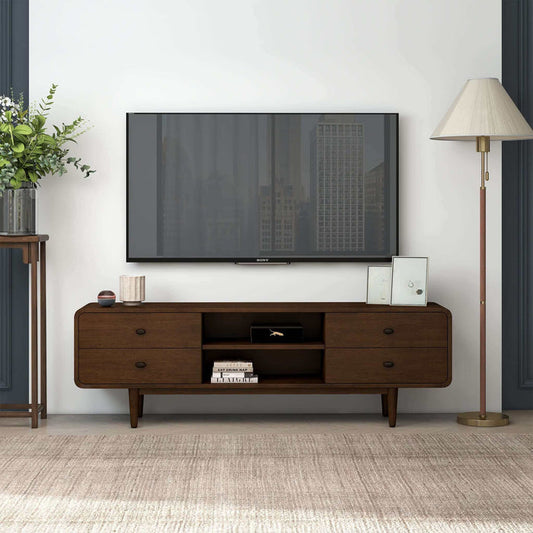 A modern living room with a wall-mounted TV above the Ashcroft Furniture Alexa MCM Solid Wood Media Console TV Stand 71, cable management, framed art and books on the console, a floor lamp with a beige shade, and a plant on the side table.