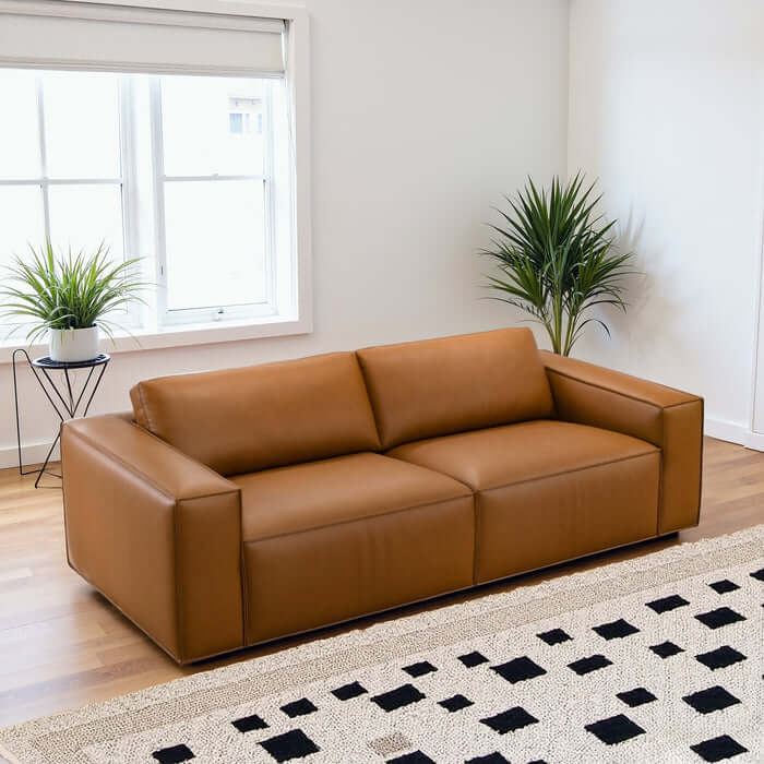 Uvalde MCM Vegan Leather Wide-Arm Sofa 92" in cognac, featuring modern design and comfort in a bright living room.