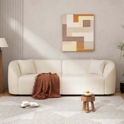 Contemporary sloped arm boucle upholstered sofa in a modern living room with art and cozy decor.