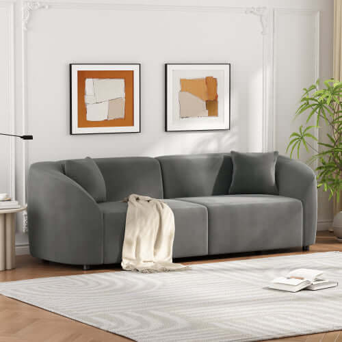 Contemporary sloped arm boucle upholstered sofa in gray with decorative cushions, set in a chic living room.