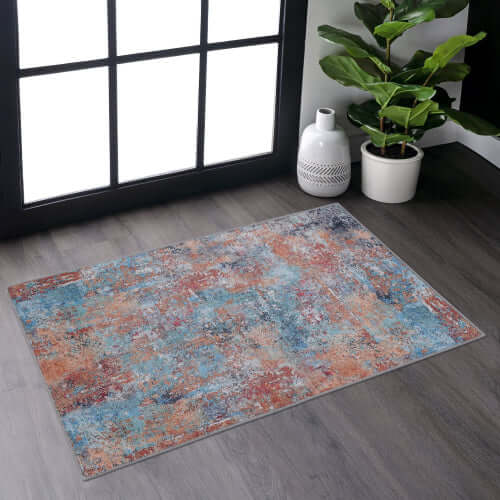 Multi-colored abstract washable area accent rug placed on hardwood floor, showcasing vibrant patterns and versatility.