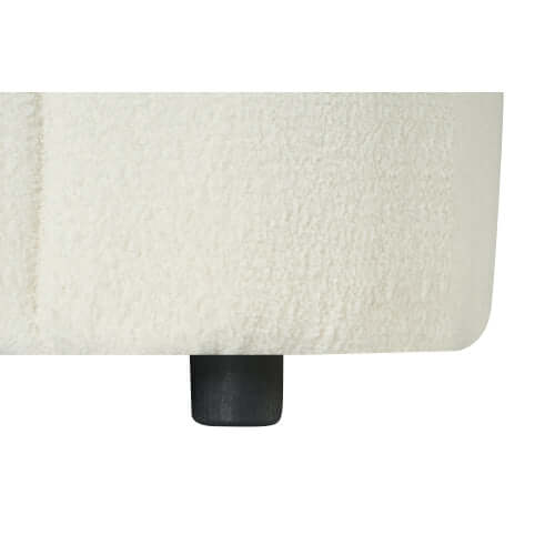 Close-up of the plush bouclé upholstery and black foot of a contemporary sofa.