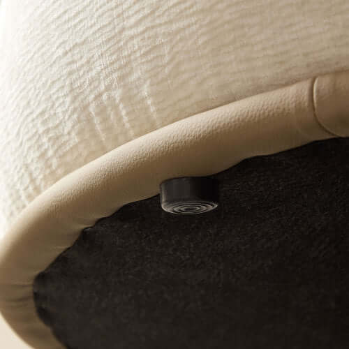 Close-up of the underside of a chaise sofa with a soft cream top and sleek black base, showcasing the design details.