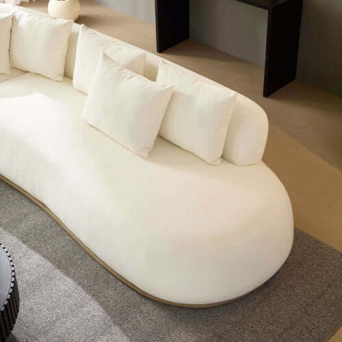 White rounded L-shaped chaise sofa sectional with plush pillows, designed for modern living spaces.