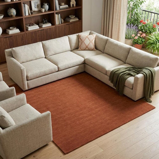 Orange Wool Hand Woven Area Rug | 9' x 13' placed beneath a light-colored sectional sofa in a cozy living room.