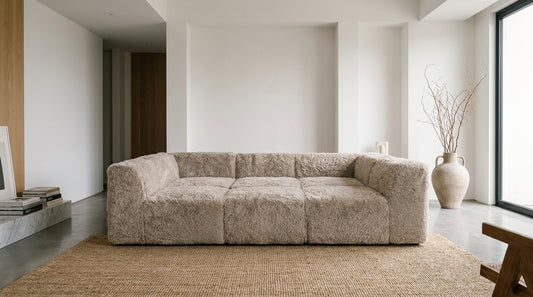 Low frameless modular sofa in soft faux fur on a jute rug in a bright minimalist living room