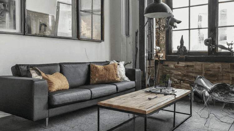 Modern living room featuring a sleek gray sofa with pillows and a rustic wooden coffee table.