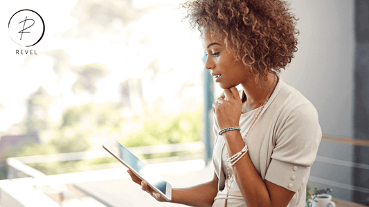 Woman with curly hair thoughtfully browsing on a tablet in a bright, modern setting.