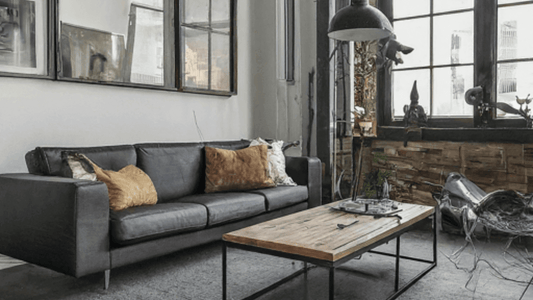 Modern living room featuring a sleek gray sofa with pillows and a rustic wooden coffee table.