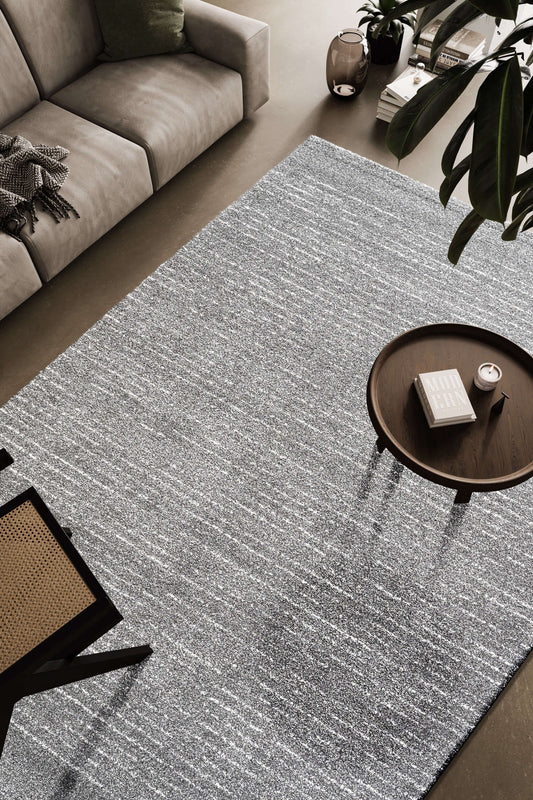 Lydia Rectangular Gray & White Striped Polypropylene Area Rug (3 Sizes) placed in a modern living room setting.