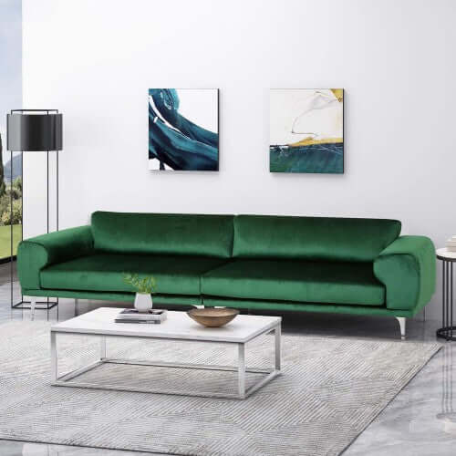 Emerald green velvet modular sofa in a modern living room with abstract art and a coffee table.