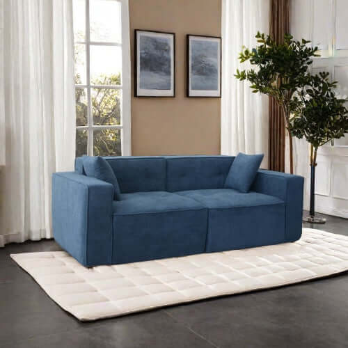Modern low profile blue memory foam sofa in a stylish living room with large windows and plant.