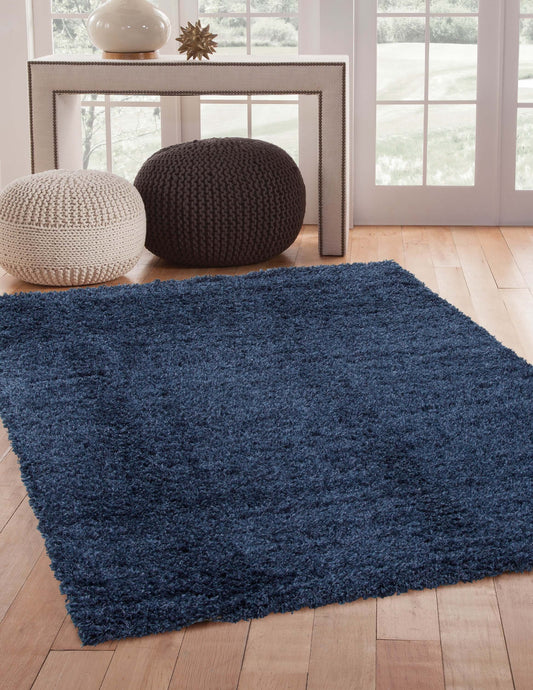 Slate blue rectangular shag area rug 5x8 on hardwood floor, surrounded by decorative poufs, ideal for stylish living spaces.
