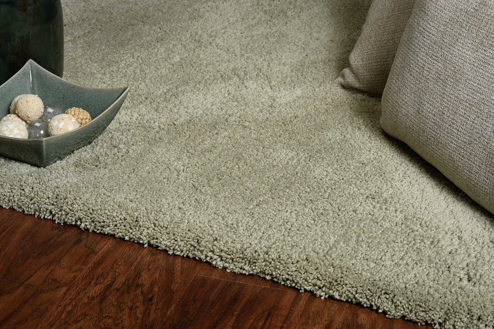 Sage Hand Woven Area Rug | 9' x 13' featuring a plush texture and cool tones on a wooden floor.
