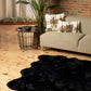 Scalloped black faux fur shag rug on wooden floor in modern living room with plants and stylish decor.