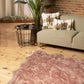 Scalloped faux fur shag rug in soft pink, enhancing a modern living room with stylish decor and cozy elegance.