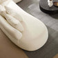 Cream rounded L-shaped chaise sofa sectional with plush pillows on a stylish rug.