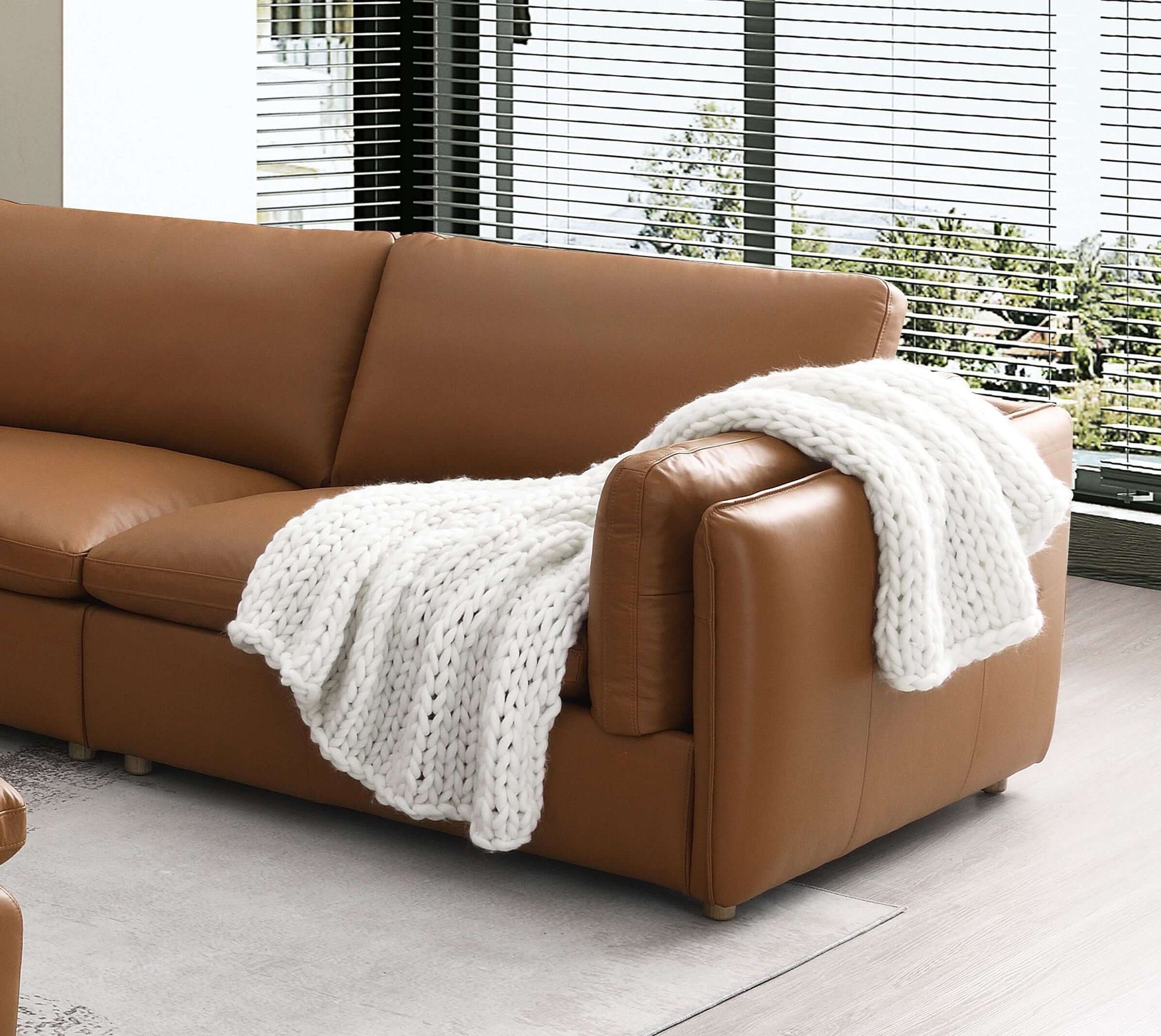 Brighton Top Grain Leather Modular Sofa in rich brown with a cozy white knitted throw blanket.