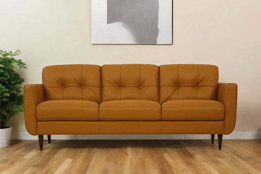 83" Orange Leather Sofa With Black Legs on a wooden floor against a light wall with a plant in the background.