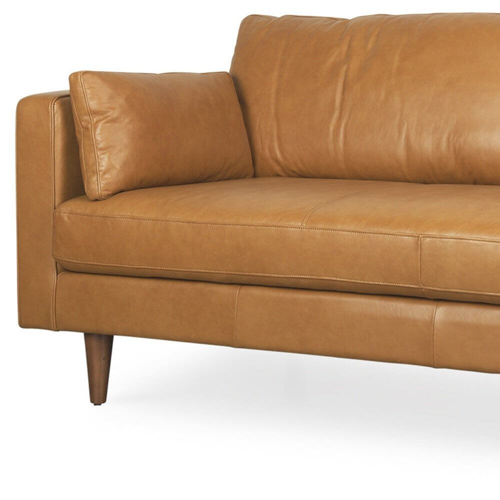 88" Tan Leather Sofa And Toss Pillows With Brown Legs with plush cushions and wooden legs.