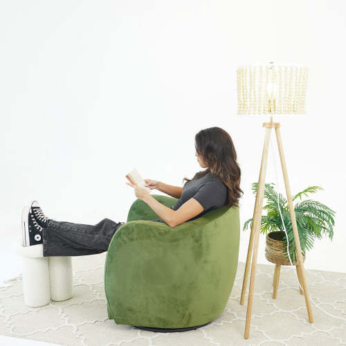 Swivel Lounge Chair in Green Velvet – Renee Modern Barrel Accent Chair with a person reading beside a stylish lamp.